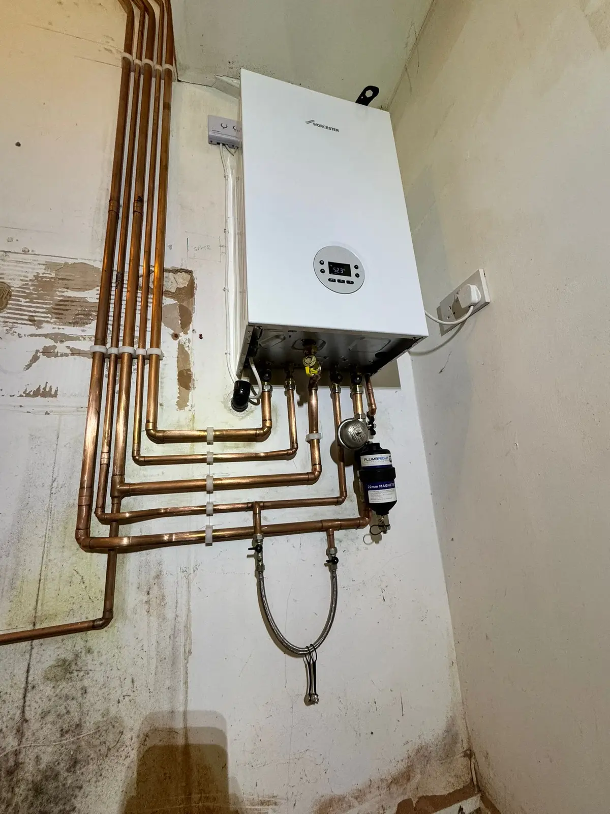 Worcester Bosch boiler on a bare plaster wall with new parallel copper pipe runs and a magnetic filter
