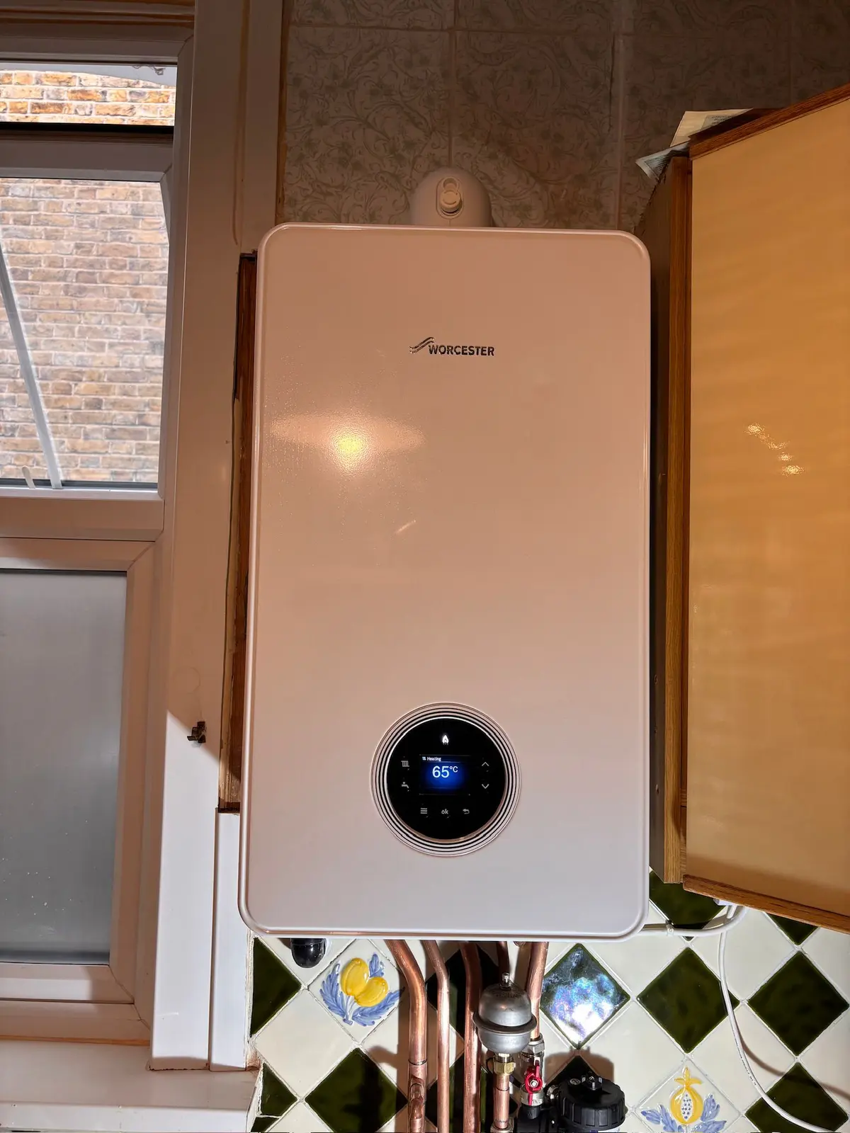 Worcester Bosch combi boiler with a digital display fitted on a kitchen wall beside the wall units