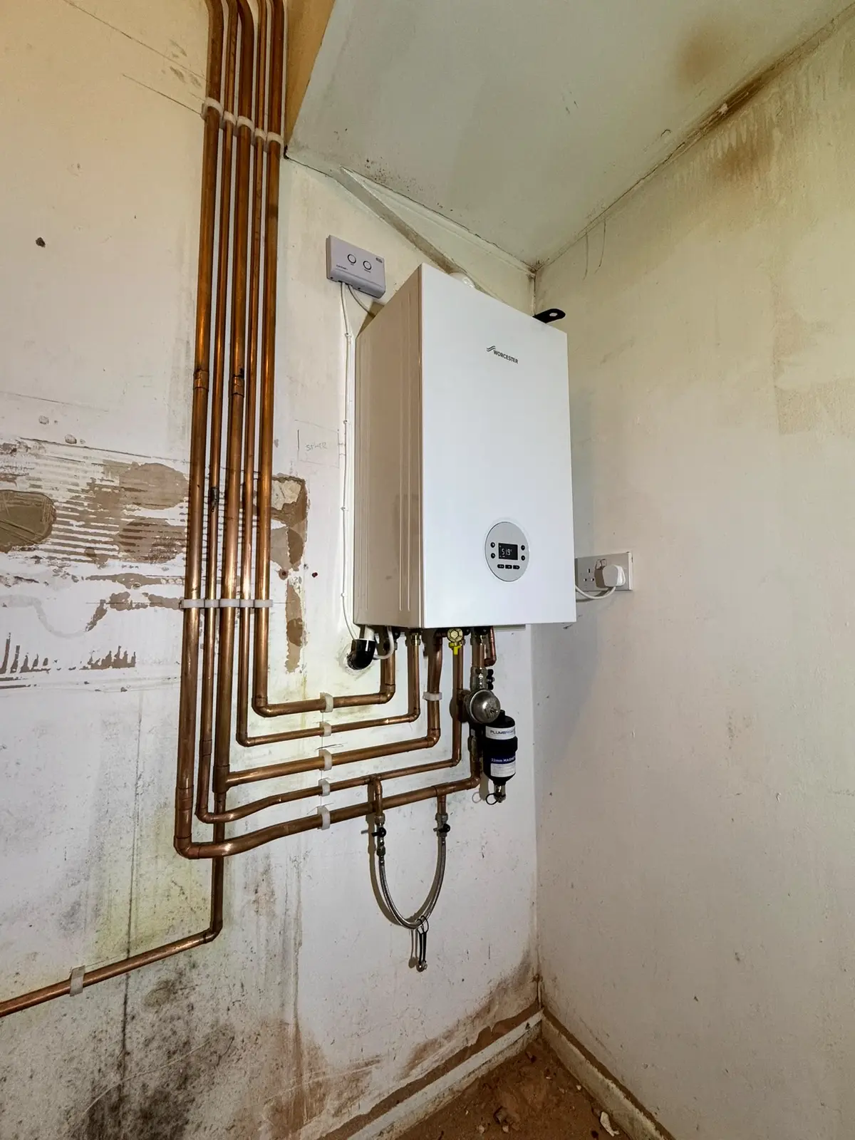 Worcester combi boiler fitted in a corner with copper pipework, a flexible connection and an inline filter